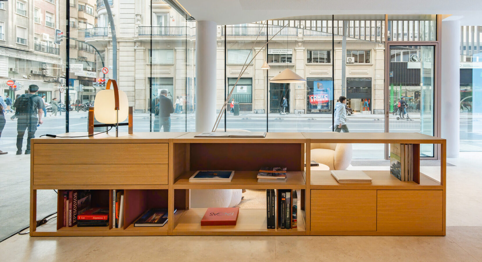 Estantería baja con libros en showroom Profusa frente a ventanales a la ciudad