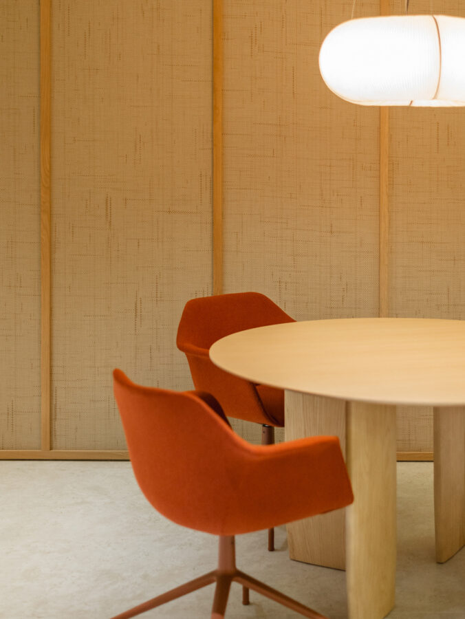 Sillas tapizadas color caldero alrededor de una mesa redonda de madera clara.