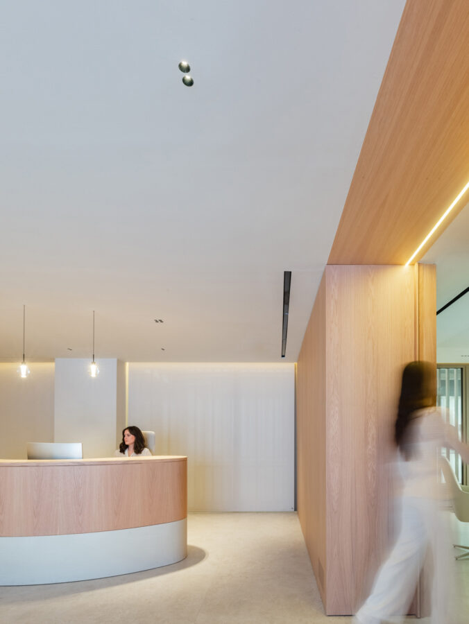 Mostrador curvo de madera con dos lámparas colgantesl sobre fondo neutro.