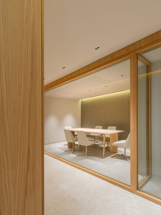 Sala de reuniones con cerramiento acristalado y mesa rectangular de madera.